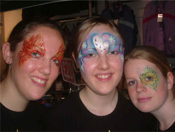 Face Painting: Three happy adult females smiling as they show off their varriously painted faces.